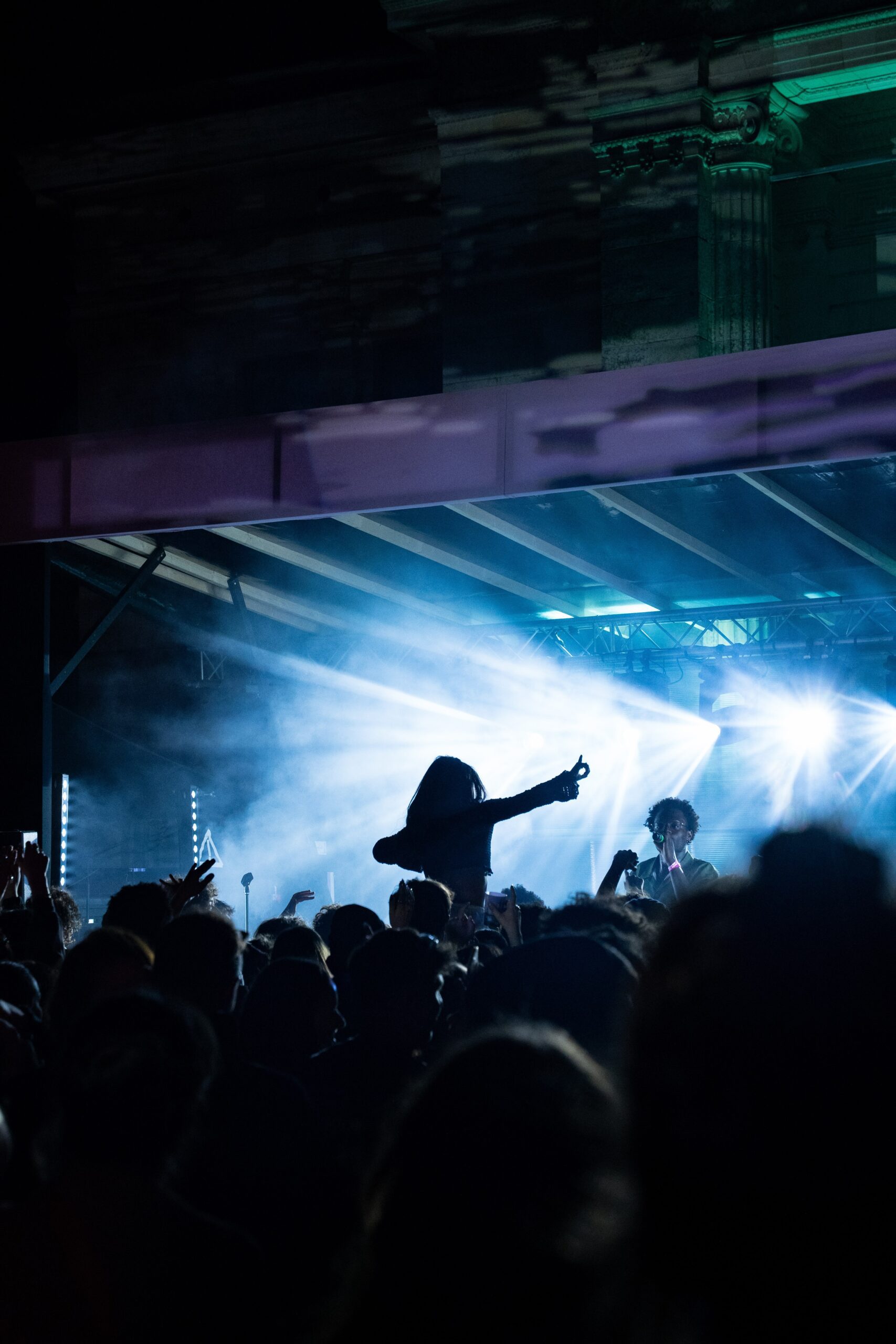 Une festivalière perchée sur les épaules d’une personne, dansant devant la scène du Festival Les 3 Éléphants, capturant l’énergie et l’ambiance du festival en plein air à Laval.