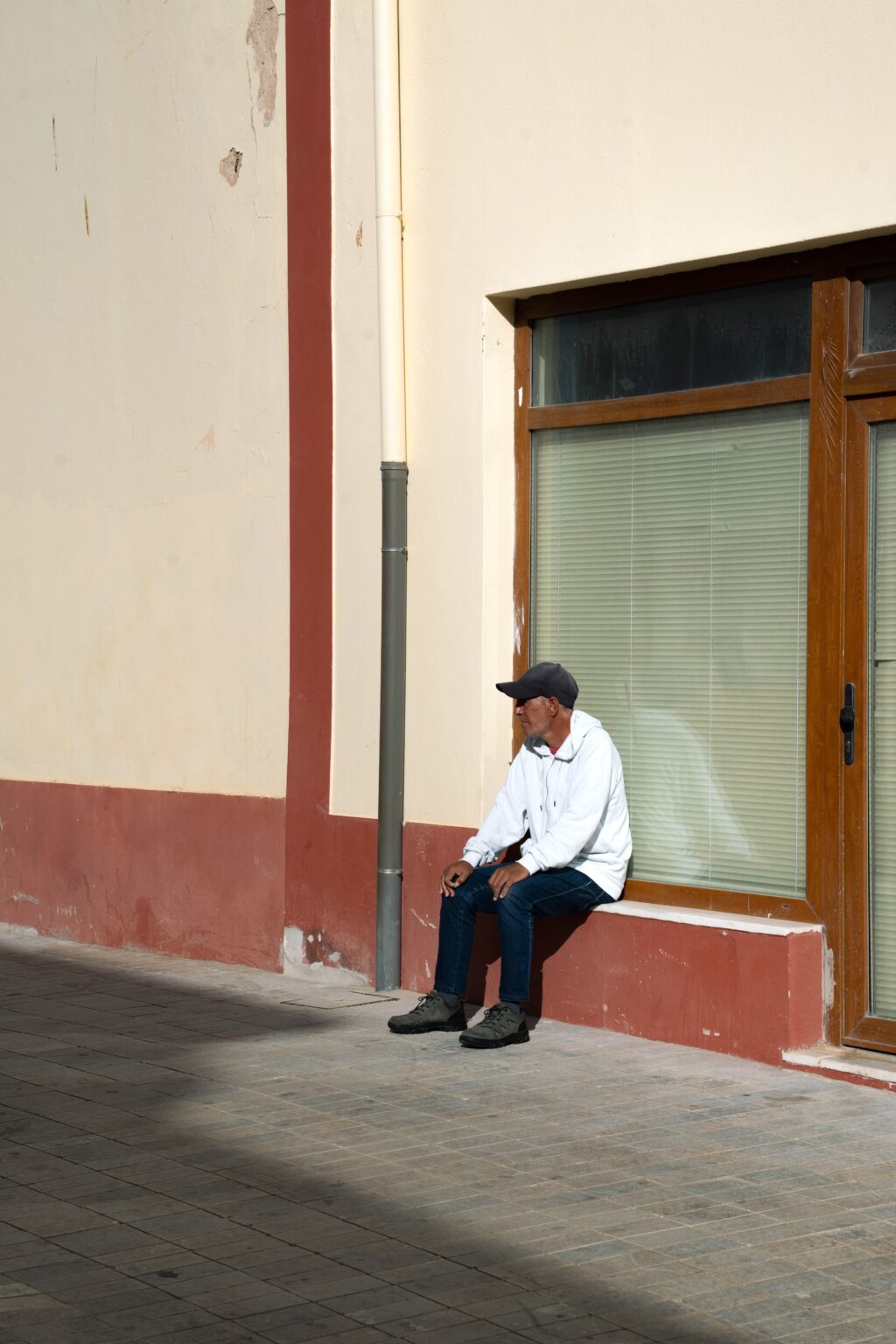 Personne assise dans la rue devant une devanture fermée, captée en photographie de rue