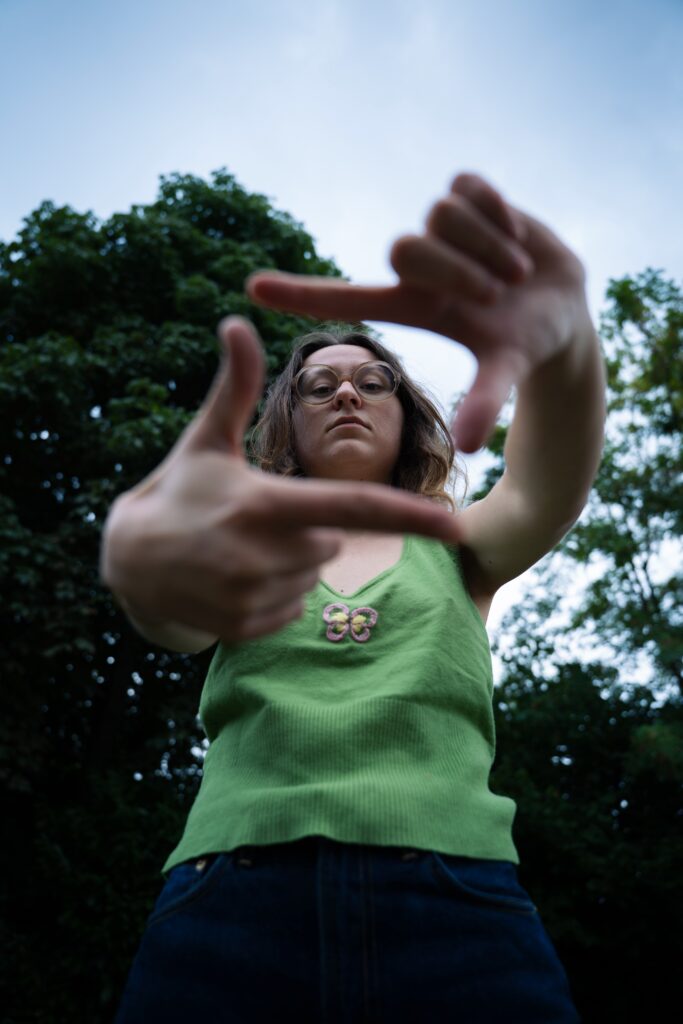 Salomé regarde la caméra en faisant un rectangle avec ses mains.